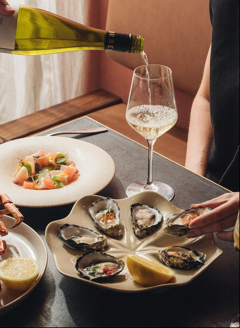 Oysters on ceramic ERRJ oyster plate with lemon and mignonette. Served with seafood dinner and white wine at Byron Bay Oyster Bar
